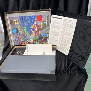 May include: A white ceramic mug with a black handle and the text "But First, Coffee" in a bold, black font. The mug is set against a blurred background, highlighting its clean design.