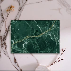 May include: A rectangular board featuring a deep forest green marble surface with intricate white and gold veining patterns throughout. The stone slab has a smooth, polished finish and sharp, clean edges, showcasing a natural, complex mineral texture.