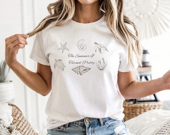 May include: White t-shirt featuring a seashell and sea life graphic with the text "The Summer I Turned Pretty". The design includes a starfish, clam, turtle, seashell, and seaweed.