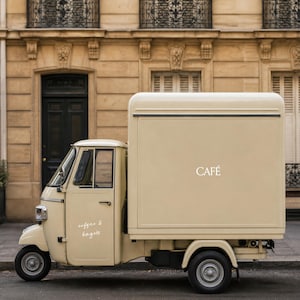 May include: A cream-colored three-wheeled utility vehicle with a box truck body. The side of the vehicle features the word CAFÉ in white lettering, while the driver door displays the text coffee & bagels in a white cursive script font.