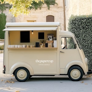 May include: A cream-colored coffee truck with the text "thepapercup COFFEE & BAGELS" on the side. The truck has an open serving window with coffee cups, a coffee machine, and other supplies. The truck is parked on a paved surface.