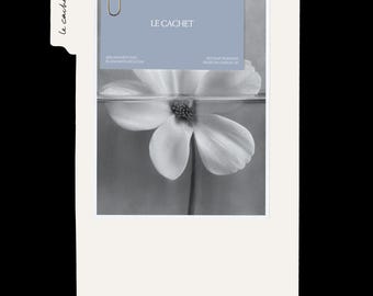 May include: A rectangular off-white file folder with a tab labeled Le Cachet. Attached with a gold paperclip is a light blue card featuring the text LE CACHET and a black and white photograph of a flower partially submerged in water.