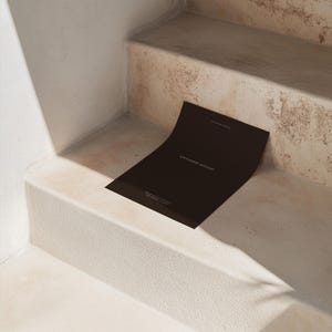 Puede incluir: Una tarjeta de maqueta de papeler&iacute;a negra en un conjunto de escaleras de hormig&oacute;n. La tarjeta est&aacute; en blanco y tiene el texto "Stationery Mockup" impreso en ella.