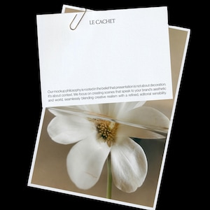 Puede incluir: Una tarjeta rectangular blanca con un clip de metal en la parte superior, con el texto LE CACHET y un párrafo sobre la filosofía de las maquetas. Debajo, una fotografía muestra una flor blanca con una fina capa de vidrio horizontal.