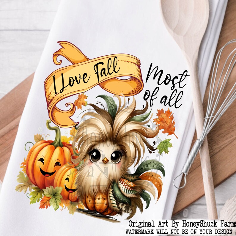 Pu&ograve; includere: Un asciugamano da cucina bianco con un'illustrazione di un pollo di cartone animato con decorazioni autunnali. Il testo "Amo l'autunno pi&ugrave; di tutto" &egrave; scritto su uno striscione sopra il pollo.