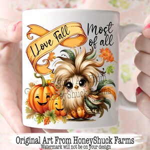 Pu&ograve; includere: Una tazza in ceramica bianca con un'illustrazione colorata di un pollo dei cartoni animati con una zucca e foglie autunnali. Il testo "Amo l'autunno pi&ugrave; di tutto" &egrave; sulla tazza.