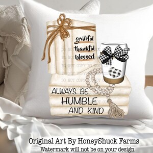 May include: A white throw pillow featuring a graphic illustration of a stack of books tied with a brown string, a coffee cup with a black and white buffalo check bow and heart, and a wooden bead garland with a tassel. Text reads grateful thankful blessed and ALWAYS BE HUMBLE AND KIND.