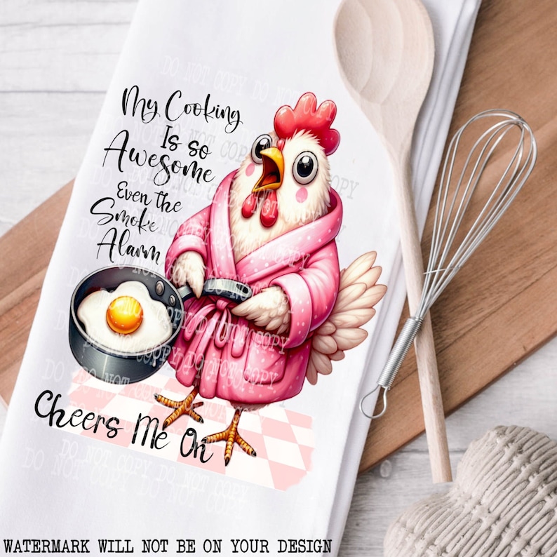 Pu&ograve; includere: Un asciugamano da cucina bianco con un'illustrazione di un pollo dei cartoni animati che indossa una vestaglia rosa e tiene una padella con un uovo fritto. Il testo sull'asciugamano dice "My Cooking Is So Awesome Even The Smoke Alarm Cheers Me On".