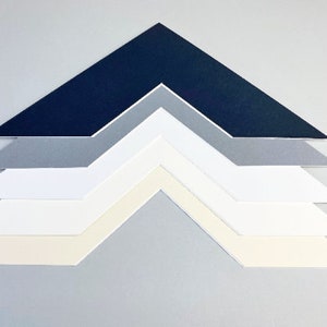 May include: An arrangement of angled, layered mount boards in navy, grey, and white. The boards are in a chevron pattern, with a light grey background.