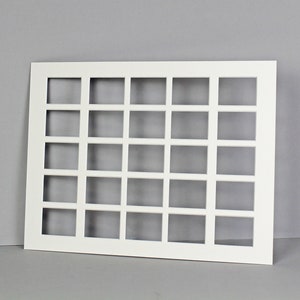 Puede incluir: Marco rectangular blanco con una cuadr&iacute;cula de 24 aberturas cuadradas. El marco est&aacute; hecho de un material blanco y tiene una superficie lisa.