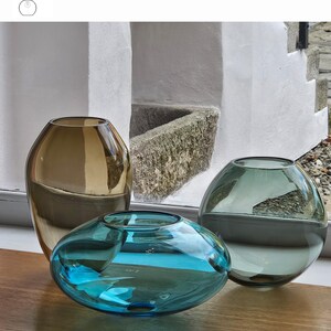May include: Three glass vases in old gold, aquamarine, and smoke grey. The vases are different shapes: one tall and rounded, one low and oval, and one spherical. The text "OPTION 9" is visible at the top.