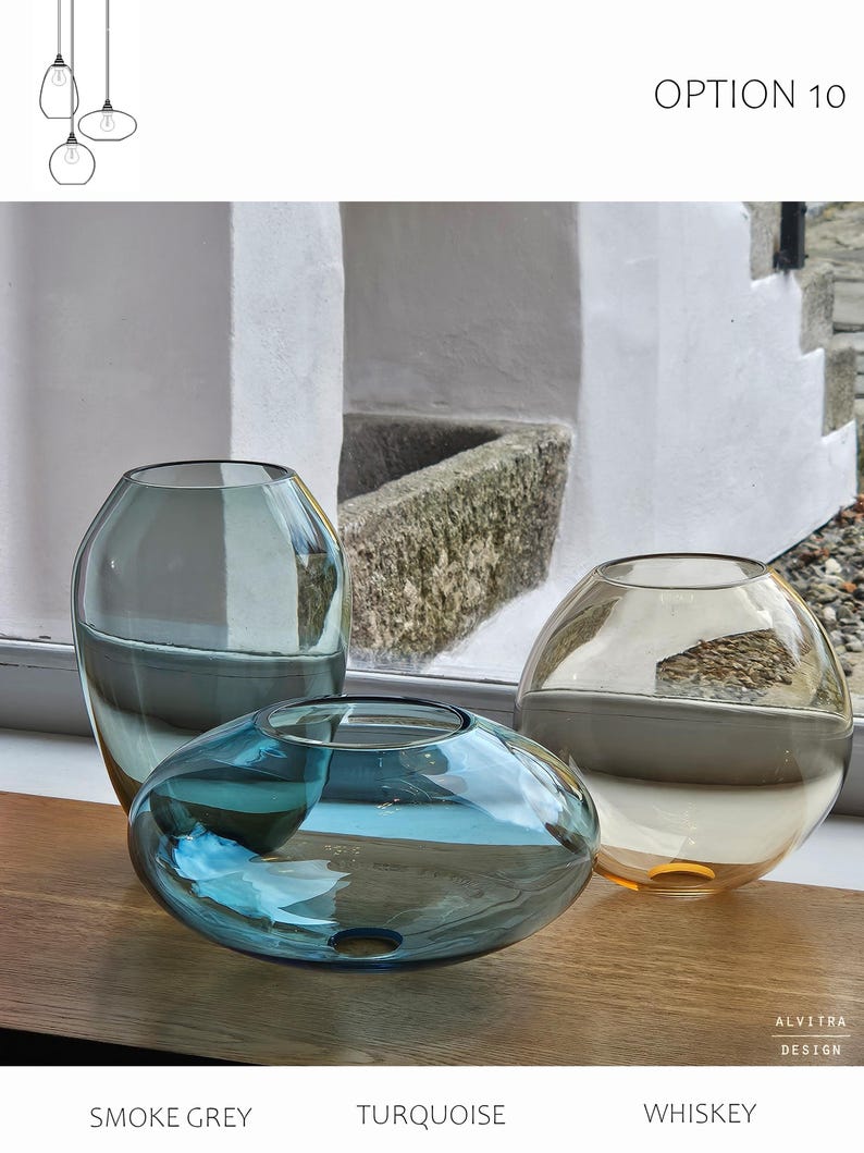 May include: Three glass vases in smoke grey, turquoise, and whiskey colors. The vases have unique shapes: a tall, rounded vase, a flattened oval, and a spherical vase. The text "OPTION 10" is at the top, and the text "SMOKE GREY", "TURQUOISE", and "WHISKEY" are at the bottom.