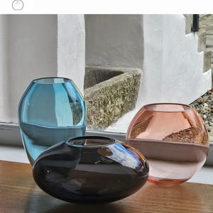 May include: Three glass vases in turquoise, smoke aubergine, and aurora colors. The turquoise vase is tall and cylindrical, the smoke aubergine vase is oval, and the aurora vase is round. The vases are displayed on a wooden surface. The text "OPTION 4" is visible.