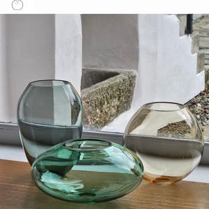 May include: Three glass vases in smoke grey, Bristol green, and whiskey colors. The Bristol vase is a flattened oval shape, while the whiskey vase is spherical. The smoke grey vase is a tall, oval shape. The text "OPTION 7" is visible.