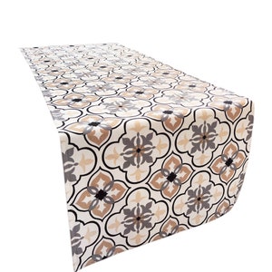 May include: A beige table runner with a geometric pattern in shades of brown, gray, and black. The pattern features repeating quatrefoils and stylized floral motifs.