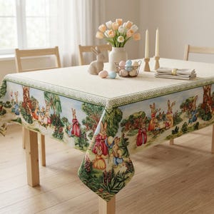 May include: A rectangular Easter-themed tablecloth with a detailed border featuring a pastoral scene with rabbits. The table is set with a vase of tulips, candles, and decorative eggs. The table is made of wood.