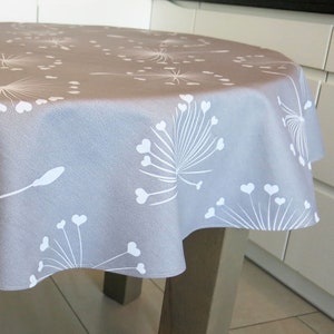 May include: A round tablecloth with a gray background and a white dandelion pattern. The dandelions are made up of small hearts.