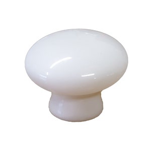 Könnte beinhalten: Vier weiße, keramik-gefertigte Knöpfe in Pilzform. Die Knöpfe haben eine glatte, glänzende Oberfläche.