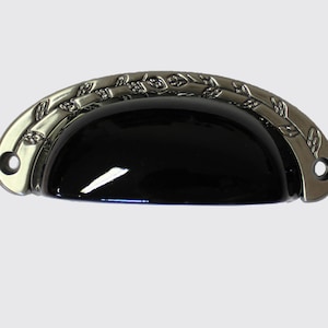 May include: Black ceramic cabinet knob with a silver finish and a leaf design.
