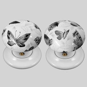 Puede incluir: Par de pomos de puerta de cerámica blanca con un diseño de mariposa en blanco y negro.