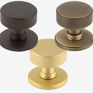 May include: Three round door knobs in different finishes: oil rubbed bronze, antique brass, and polished brass. Each knob has a textured, ridged design.
