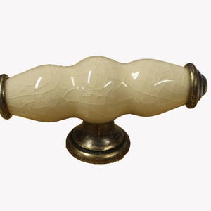 May include: A cream ceramic cabinet knob with a crackled finish and a gold-toned metal base.