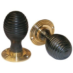 May include: Two black and brass door knobs with a ribbed design. The knobs are round and have a brass base.
