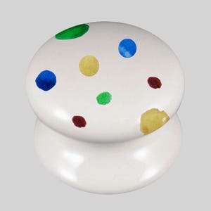 May include: White ceramic knob with a polka dot design. The dots are in various colours, including green, blue, yellow, and red.