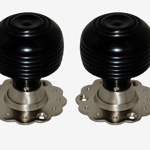May include: Two black wooden door knobs with silver metal bases and decorative edges. The knobs have a grooved design.