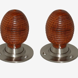 May include: Two brown wooden door knobs with a silver base. The knobs have a ribbed design.