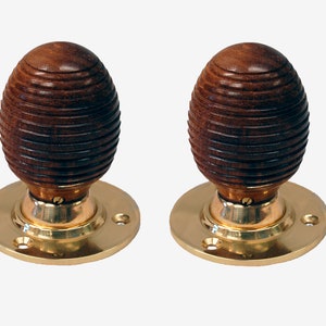 Può includere: Coppia di pomelli per porte in legno marrone con basi in ottone. I pomelli hanno un design a coste.