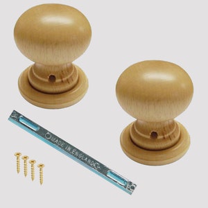 Può includere: Due pomelli per porte in legno di forma rotonda e colore marrone chiaro. I pomelli sono mostrati con una piastra di montaggio in metallo e viti. La piastra di montaggio ha il testo "MADE IN ENGLAND" stampato su di essa.