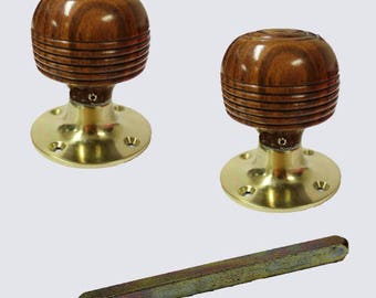 Op de afbeelding: Twee houten deurknopjes met messing bases en een vierkante messing spindel. De knoppen zijn donkerbruin met een houtnerfpatroon.
