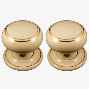 May include: A pair of cream-coloured door knobs with gold trim. The knobs are round with a gold band around the top and base. The base is also cream-coloured with a gold trim. Suitable for a cabinet or door.