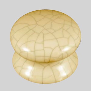 Puede incluir: Un par de pomos de armario de cerámica de color crema con un acabado craquelado.