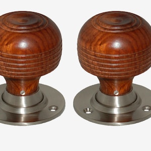 May include: Two wooden door knobs with a silver base. The knobs are round and have a grooved pattern.