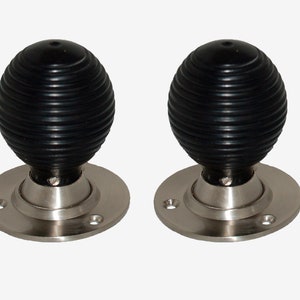 Può includere: Due pomelli per porte neri con base argentata e design a coste.