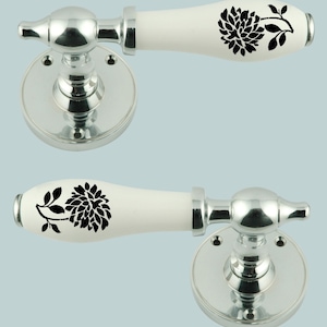 May include: Two chrome door handles with white ceramic levers. The levers have a black floral design.