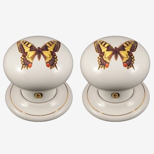 May include: Pair of white ceramic door knobs with a gold trim. Each knob features a yellow butterfly with brown and red markings.