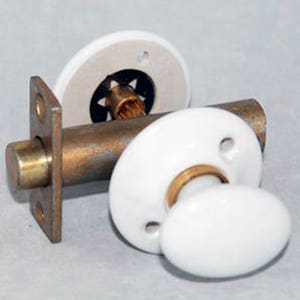 May include: A pair of white porcelain door knobs with a brass spindle. The knobs have a simple, classic design.