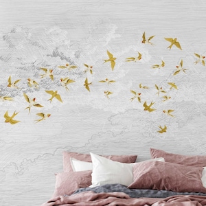 May include: A white and gray wallpaper with a flock of gold birds flying in a diagonal line across the background. The wallpaper is behind a bed with pink and white pillows.