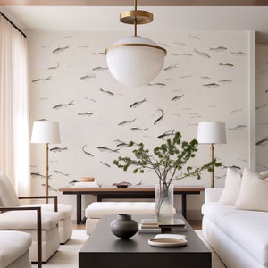 May include: A living room interior with white walls featuring a wallpaper pattern of stylized fish in shades of gray. The room is furnished with a white sofa, two white armchairs, a coffee table, and two floor lamps. A large, round, white pendant light hangs from the ceiling. A vase with green branches sits on the coffee table.