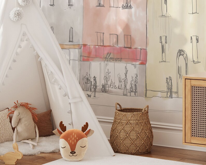 Op de afbeelding: Een witte tipi-tent met bruine kwastjes en pompoenen, een bruin en oranje pluche herten speelgoed, een bruin en wit pluche paard speelgoed, een bruine rieten mand en een witte muur met een handgetekende illustratie van een straat in de stad met een winkel die "Flowers" zegt.