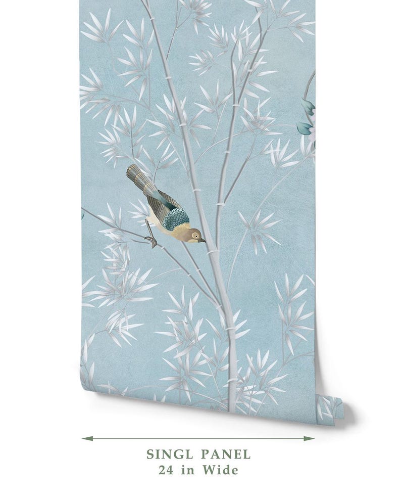 Puede incluir: Un rollo de papel tapiz con fondo azul claro, tallos de bamb&uacute; blancos y un p&aacute;jaro con plumas marrones, azules y grises. El texto en la parte inferior indica un ancho de panel &uacute;nico de 61 cm, mostrado con una flecha de medici&oacute;n doble.