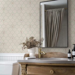 Peut inclure: Une scène de salle de bain avec une vanité en bois, un robinet doré et un grand miroir encadré de noir. Le papier peint présente un motif répété de visages de chats dans un treillis. Un vase blanc contient des plantes séchées.