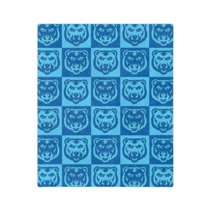 May include: A rectangular fabric blanket featuring a repeating checkerboard pattern of bear faces. The design alternates between squares of dark blue and light blue, with each square containing a stylized, symmetrical illustration of a bear head.