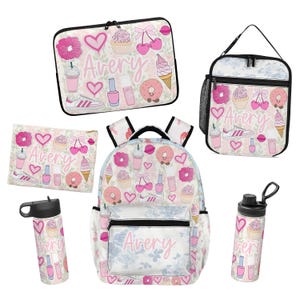 May include: A set of school supplies including a backpack, lunch bag, pencil case, laptop sleeve, and two water bottles. Each item features a pink and white pattern with hearts, cupcakes, donuts, cherries, and the name Avery printed in script.