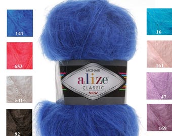 May include: A skein of Alize Mohair Classic yarn in a vibrant blue hue. The label displays the brand name and product details. Surrounding the main skein are color swatches in shades of blue, pink, beige, brown, and purple, each with a corresponding number.