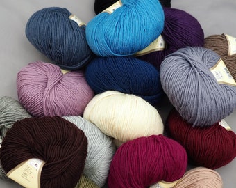 Puede incluir: Una colección de ovillos de lana coloridos en varios tonos, incluyendo azul, morado, gris y marrón. La lana está dispuesta en un montón, mostrando la textura y las variaciones de color. Ideal para proyectos de tejido y ganchillo.