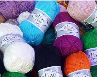 May include: A collection of colorful yarn skeins, including shades of blue, purple, green, orange, black, and pink. Each skein is labeled with the brand "Alize Extra". The yarn is arranged in a pile, suggesting a craft or knitting supply.